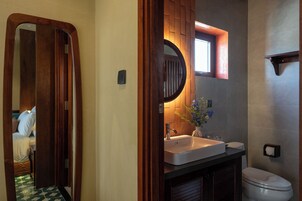 A bathroom with a wooden vanity, a sink, a toilet, and a mirror.