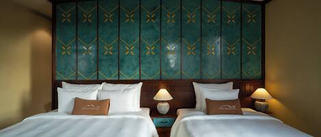 A hotel room with two beds, a wooden headboard, and a green patterned wall.