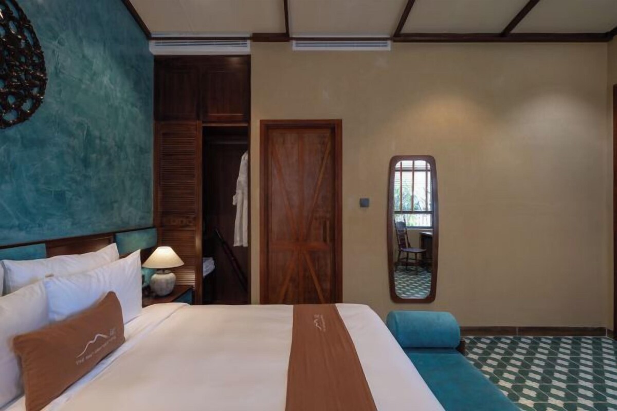 Une chambre d’hôtel avec un grand lit, une armoire, un miroir et un sol à carreaux.