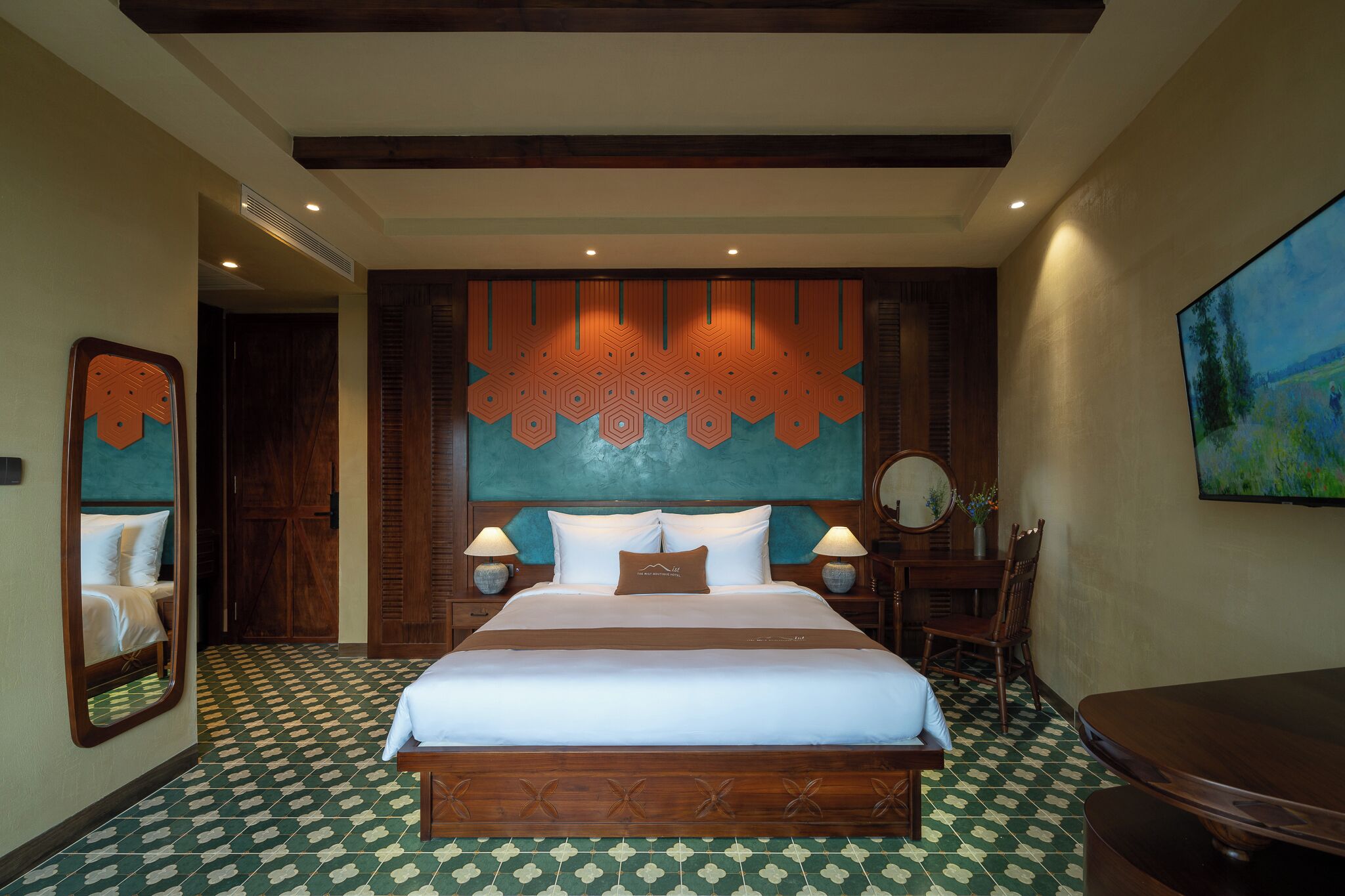 A hotel room with a large bed, wooden headboard, and a patterned floor.