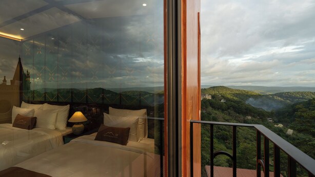 A bedroom with a large window overlooking a mountainous landscape.