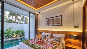Une chambre d’hôtel moderne avec un grand lit, une petite table de chevet, une œuvre d’art accrochée au mur et une vue sur une piscine.