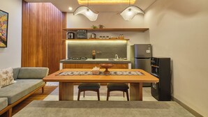 Une cuisine moderne avec un plafond en bois, des luminaires suspendus, une table à manger avec deux chaises et un réfrigérateur.