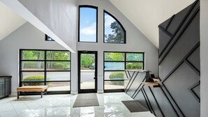 A modern interior with a bench, a desk, and a view of the outdoors through large windows.