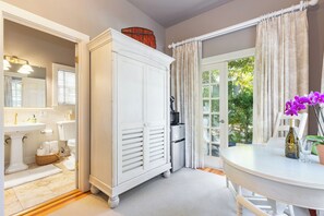 A bathroom with a white vanity, a mirror, and a window with curtains. - Cedar Mansion Estate and Bungalows- Burbank Suite (Sonoma)