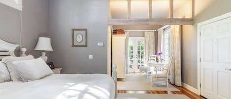 A bedroom with a bed, bedside table, lamp, and a framed picture on the wall.