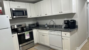 A modern kitchen with white cabinets, stainless steel appliances, a granite countertop, and a coffee maker. - Exclusive Escape- 1 mile to metro w/ FULL kitchen! (McLean)