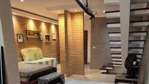 Un coin repas avec une table dressée pour deux personnes, un escalier et un lit en arrière-plan.