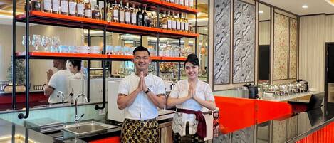 A bar area with shelves of liquor bottles, a counter with a sink, and a decorative wall with patterned panels.