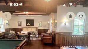 Une pièce chaleureuse avec une table de billard, des sièges confortables et une cheminée.