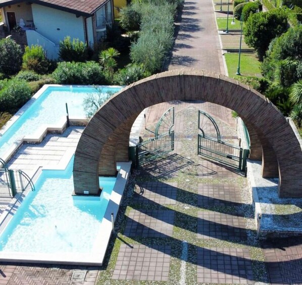 Una piscina con un arco de piedra y un sendero empedrado.