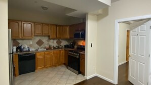 A kitchen with wooden cabinets, a stainless steel refrigerator, a microwave, and a stove. - Cjay Homes (Jersey City)
