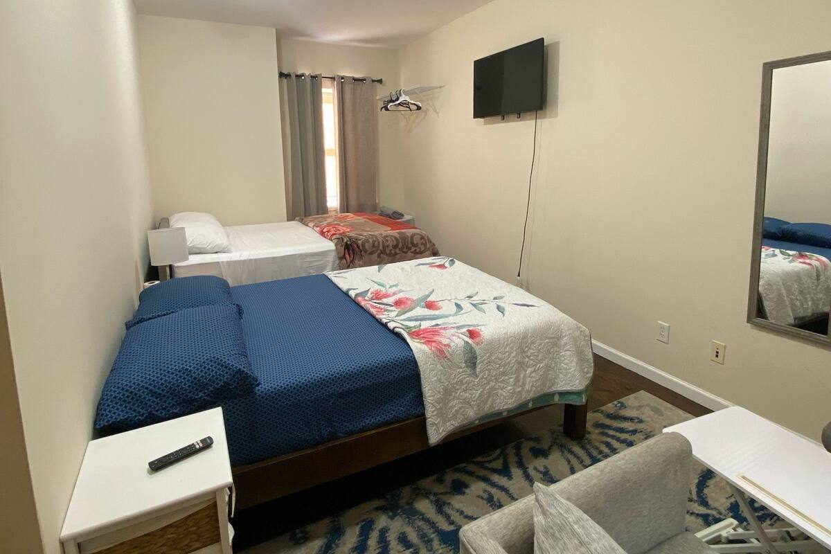 A hotel room with a bed, a desk, a chair, a TV, and a mirror.