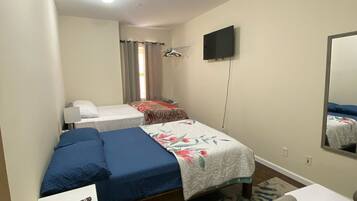 A hotel room with a bed, a desk, a chair, a TV, and a mirror.