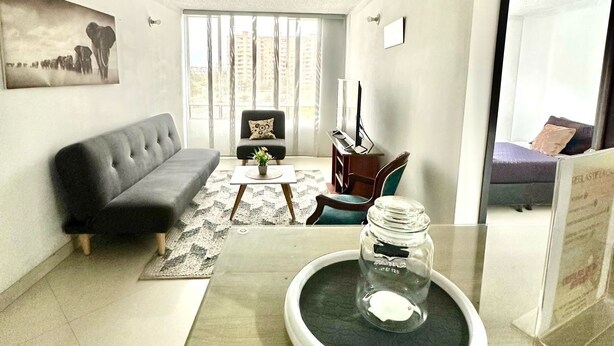 A modern living room with a black sofa, a coffee table, and a dining table with a glass jar. - Charming 2-bedroom apartment in enchanting Bogotá with WiFi (Bogotá)