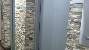 A hallway with stone-patterned walls, a tiled floor, and a closed elevator door. - Charming 2-bedroom apartment in enchanting Bogotá with WiFi (Bogotá)