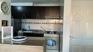 A modern kitchen with dark cabinets, a gas stove, a sink, and a clock on the wall. - Charming 2-bedroom apartment in enchanting Bogotá with WiFi (Bogotá)