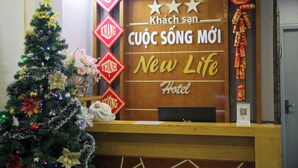 A reception desk with a Christmas tree and decorations, and a sign for 'New Life Hotel'.
