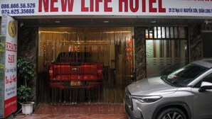 The exterior of New Life Hotel with a red car parked in front.