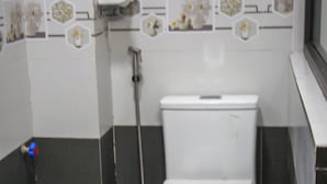 A bathroom with a toilet, a shower, and a hand dryer.