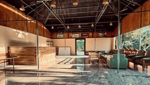A spacious room with a high ceiling, wooden walls, and a large window offering a view of greenery. - KAZIRANGA ECO VILLAGE RESORT (Kaliabar)