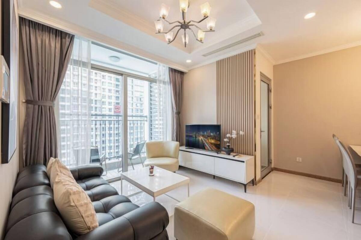 A modern living room with a sofa, ottoman, coffee table, TV, and a dining area.