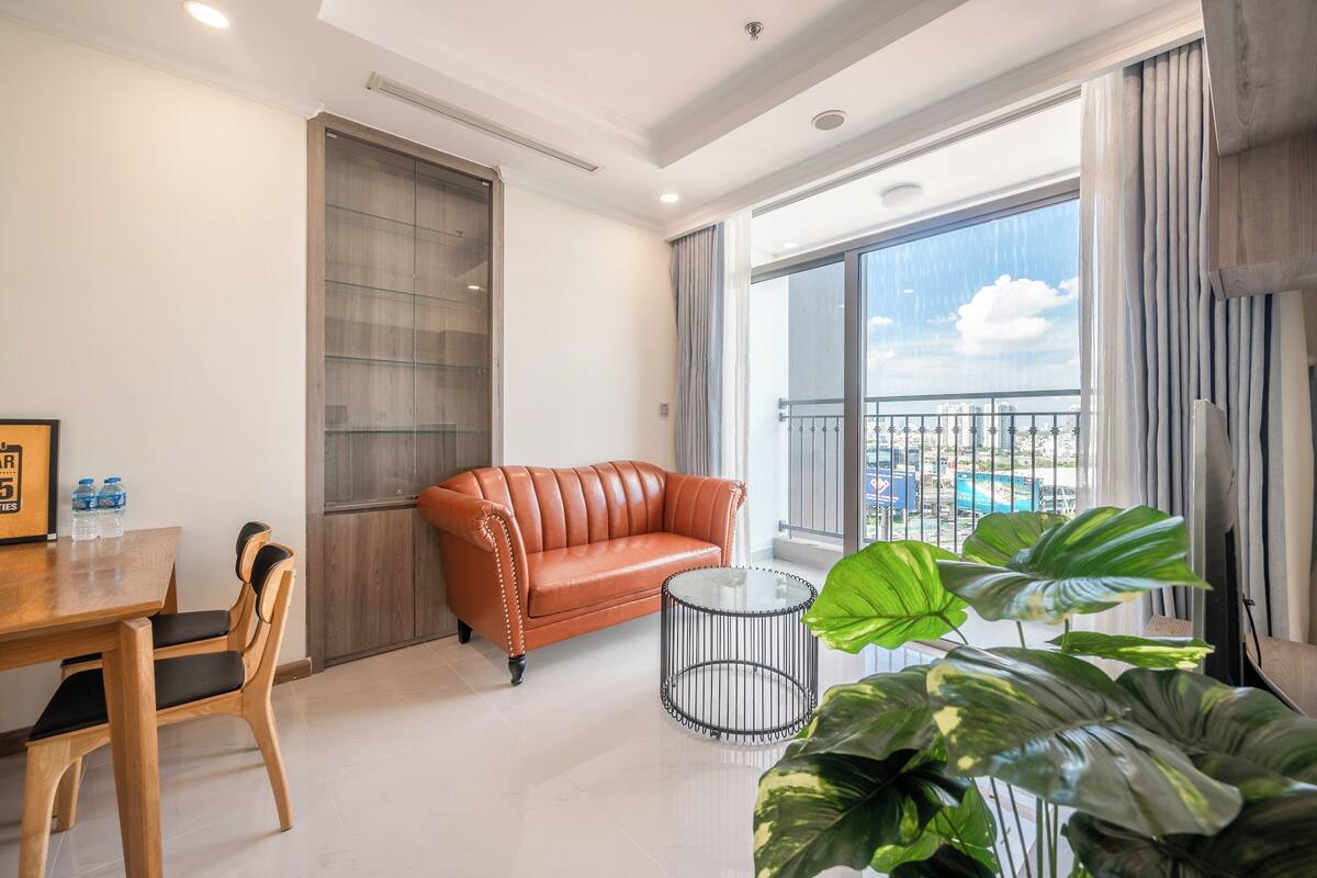 A modern living room with a leather sofa, a glass coffee table, and a dining area with a wooden table and chairs.