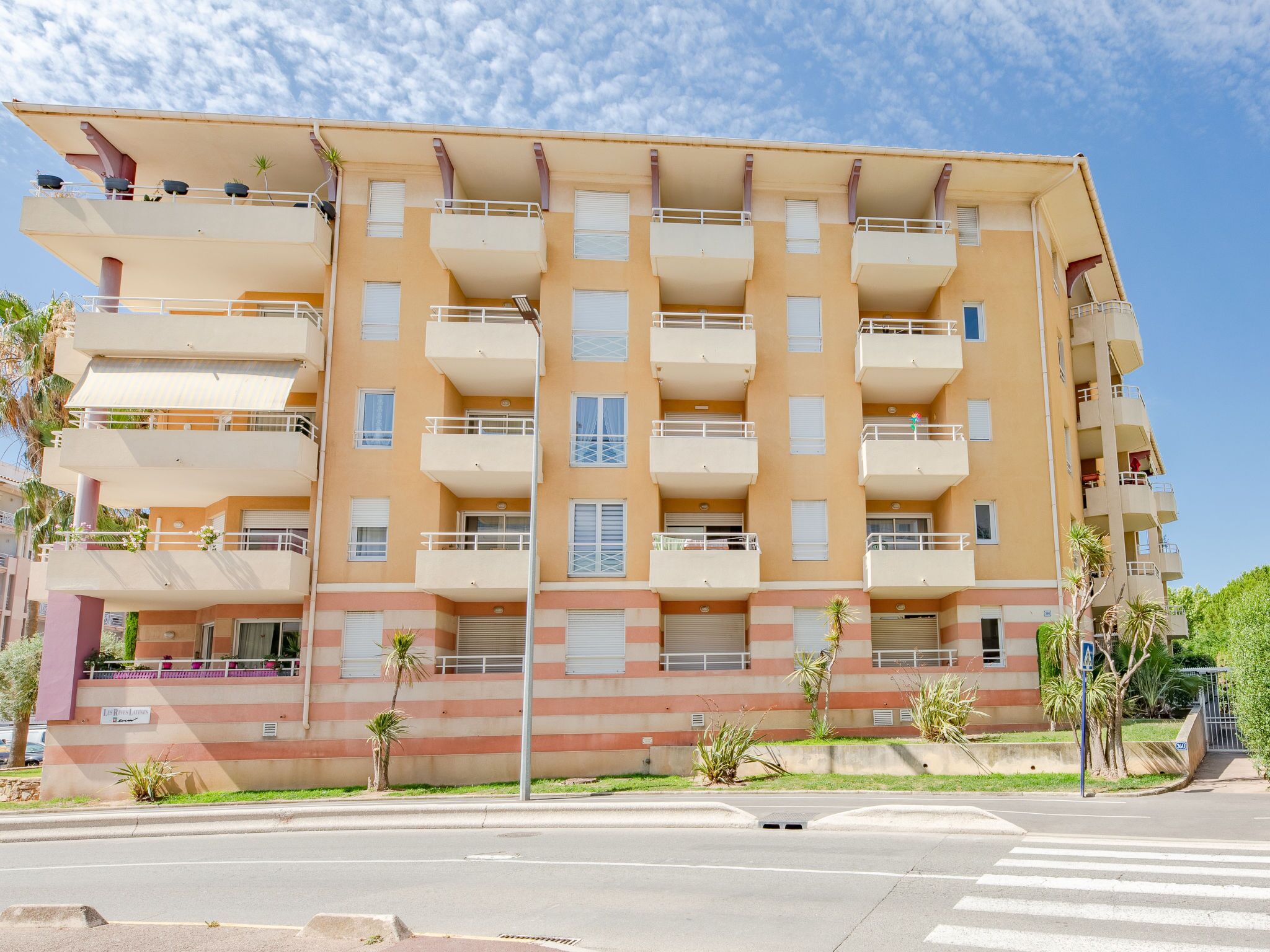Um edifício residencial com vários andares, varandas, telhado plano e uma placa indicando um restaurante.