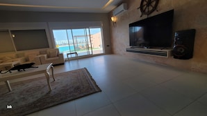 Una sala de estar moderna con un televisor grande, un sofá, una mesa de centro y una alfombra.