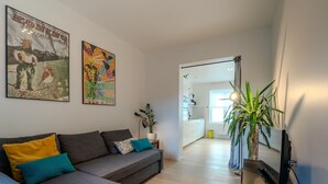 A modern living room with a grey sofa, a TV on a wooden stand, and two colorful posters on the wall. - Sea of Tranquility with terrace by Interhome (Oostende)