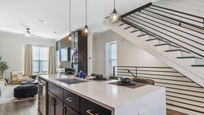 A modern kitchen with a central island, black cabinets, and pendant lighting. - Luxury Downtown Townhouse w/ Game Room and Gated Lot (Tyler)