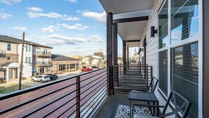 A balcony with a view of the street and buildings. There are two tables and chairs on the balcony. - Luxury Downtown Townhouse w/ Game Room and Gated Lot (Tyler)