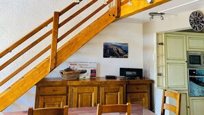A wooden staircase with a dining area below, including a table and chairs.