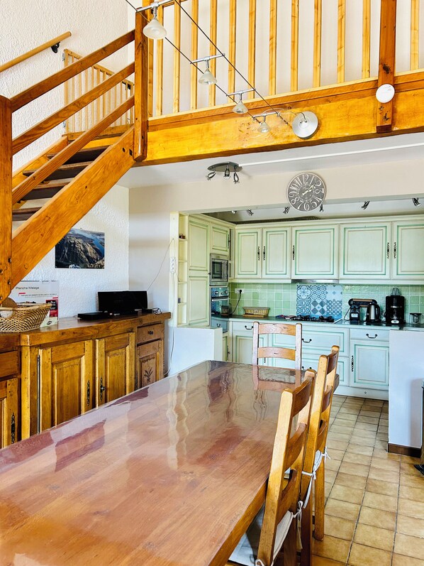 Una cocina con armarios de madera, una mesa de comedor y una escalera.