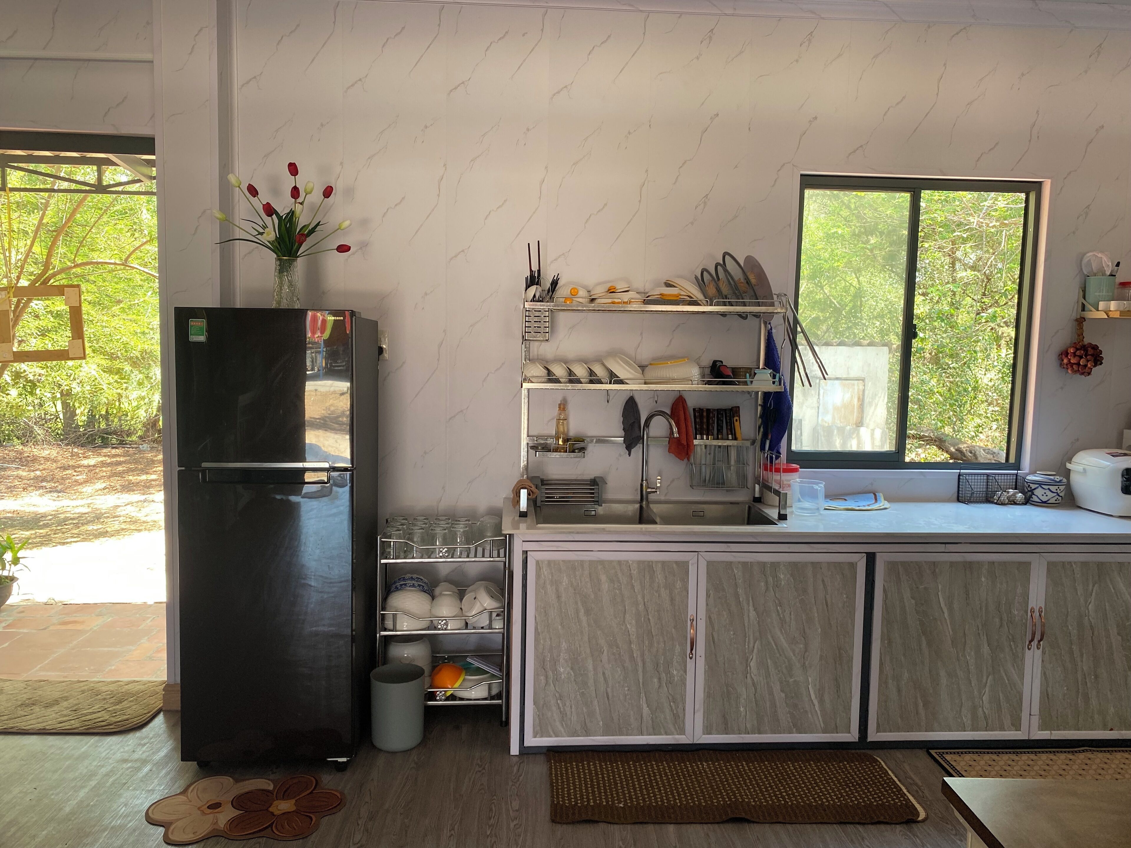 A compact kitchen with a refrigerator, a sink, and a window with a view of greenery.