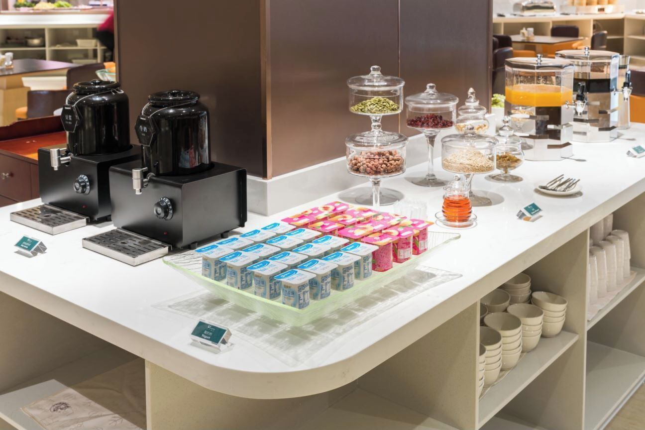 Een ontbijtbuffet met koffieautomaten, diverse etenswaren en drankdispensers.