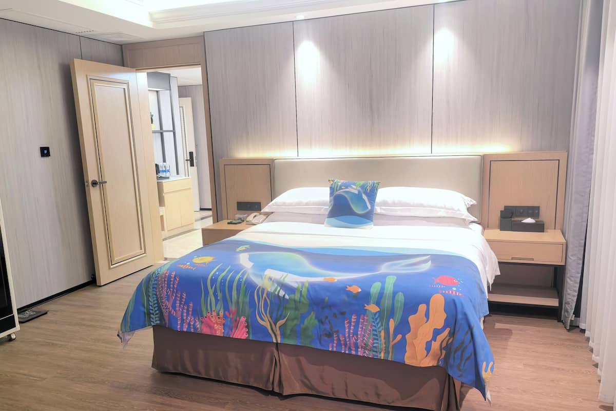 A hotel room with a bed, nightstands, a desk, and a bathroom visible through an open door.