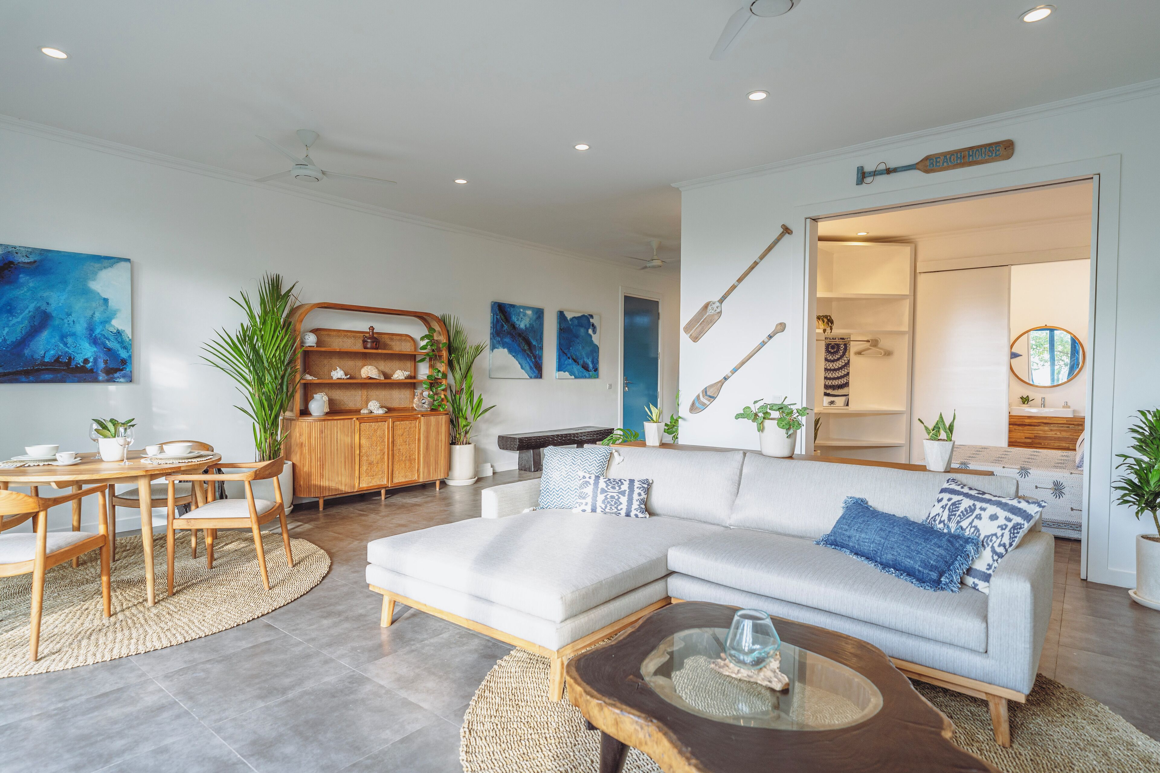 A modern living room with a sectional sofa, a wooden coffee table, and a dining area with a round table and chairs.
