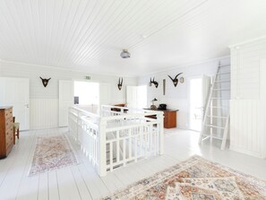 A spacious room with white wooden floors, a white railing, and a staircase.