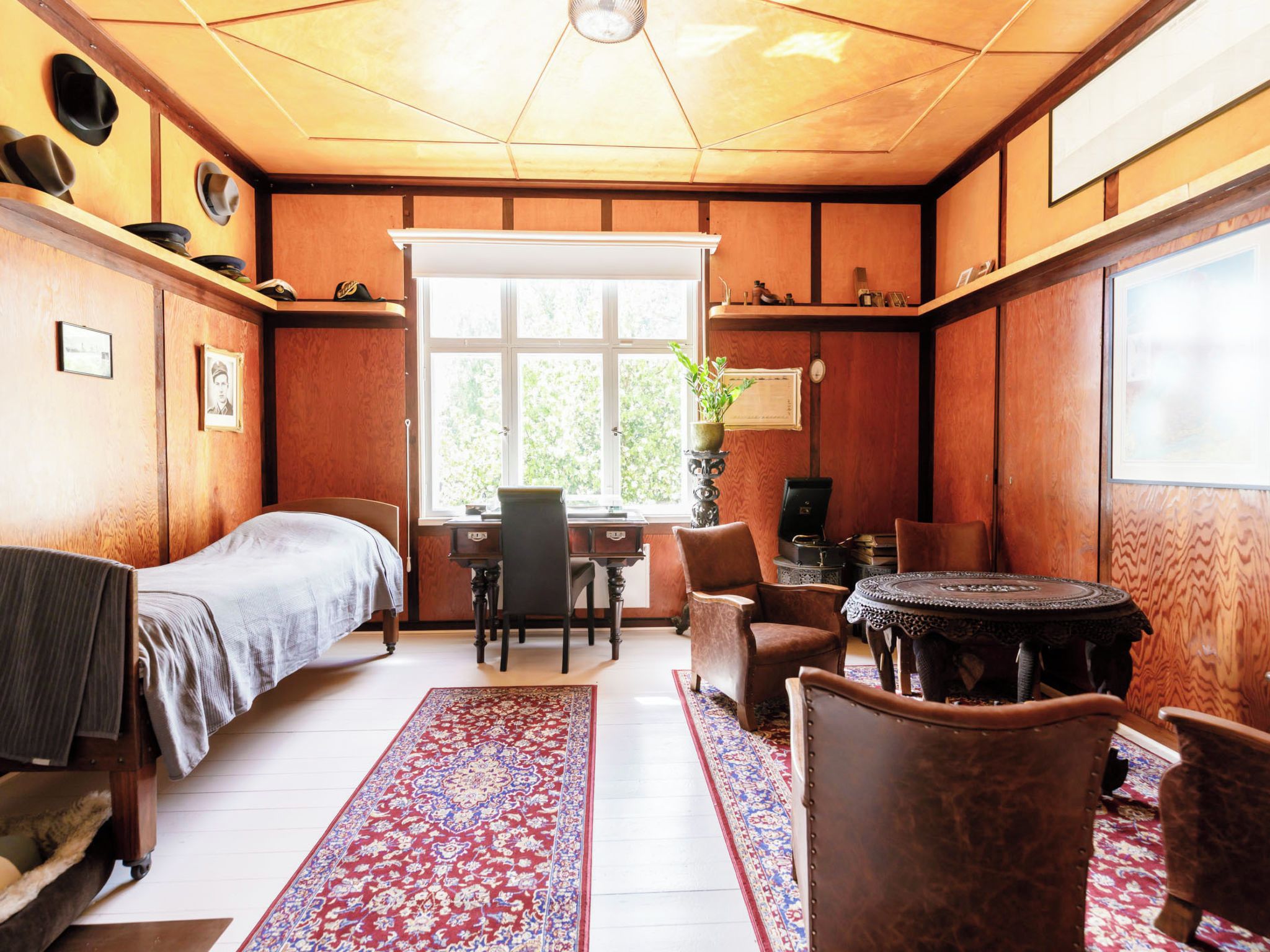 Een kamer met een bed, een bureau, een stoel, een tafel en een raam.