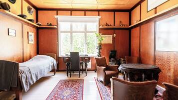 Een kamer met een bed, een bureau, een stoel, een tafel en een raam.