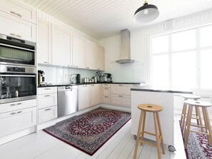 Eine moderne Küche mit weißen Schränken, Edelstahlgeräten, einer schwarzen Arbeitsplatte und einem gemusterten Teppich.