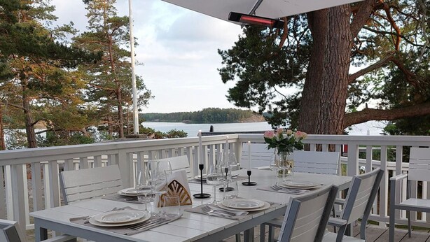 A deck with a table set for dining, overlooking a body of water. - Kapteenin huvilat by Interhome (Parainen)