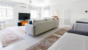 A spacious living room with a large sofa, a TV, and a sailboat decoration. - Kapteenin huvilat by Interhome (Parainen)