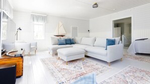 A spacious living room with a white sectional sofa, a small sailboat decoration, and a wooden desk. - Kapteenin huvilat by Interhome (Parainen)