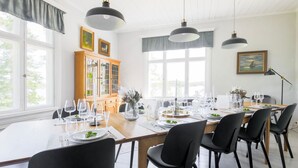 A dining area with a long table set for six, black chairs, and pendant lighting. - Kapteenin huvilat by Interhome (Parainen)