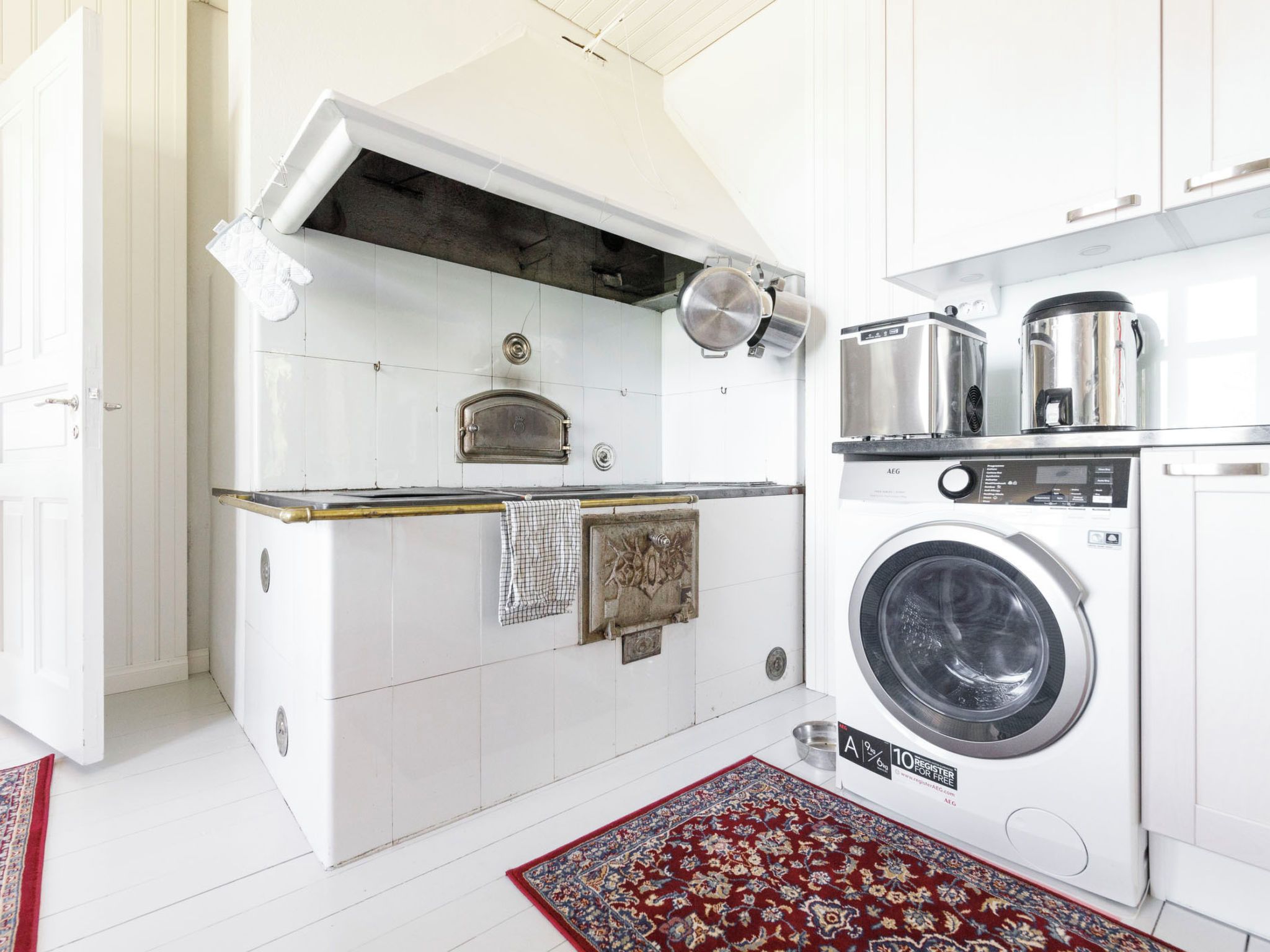 Cocina compacta con horno integrado, lavadora y un lavamanos pequeño.