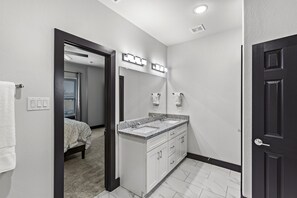 A bathroom with a double sink, a large mirror, and a dark door.