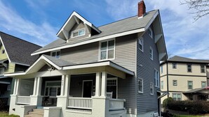A two-story house with a front porch, a chimney, and a small window.