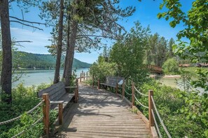 Une promenade en bois agrémentée de bancs, entourée d’arbres et offrant une vue sur un lac.